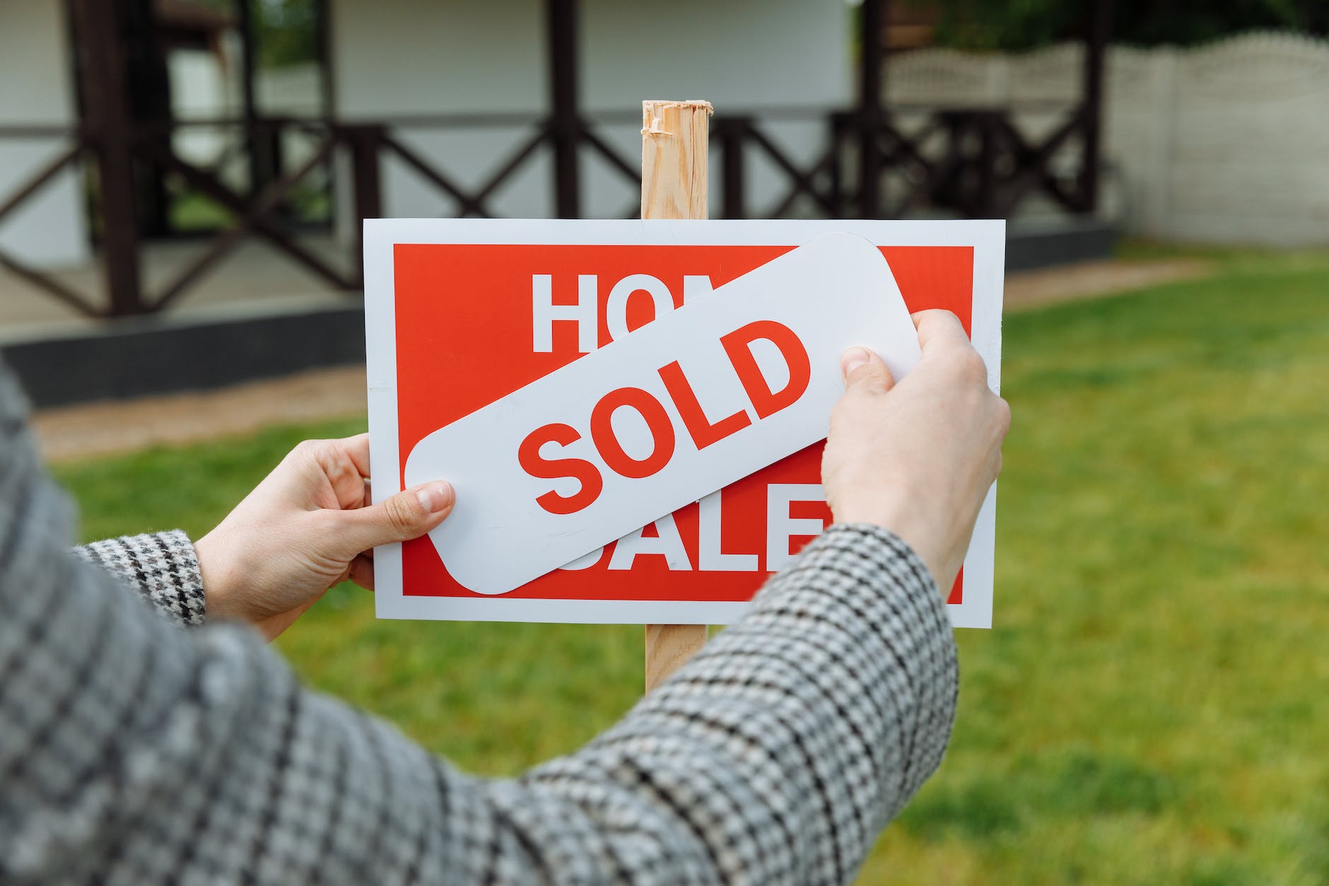 shallow focus photo of a realtor posting a sold sticker